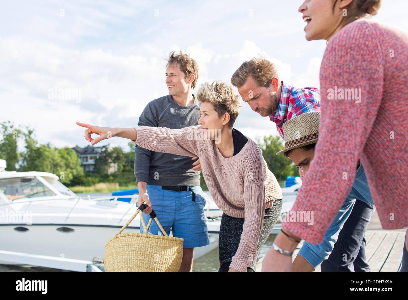 Woman showing something to friends while preparing for picnic at harbor Stock Photo