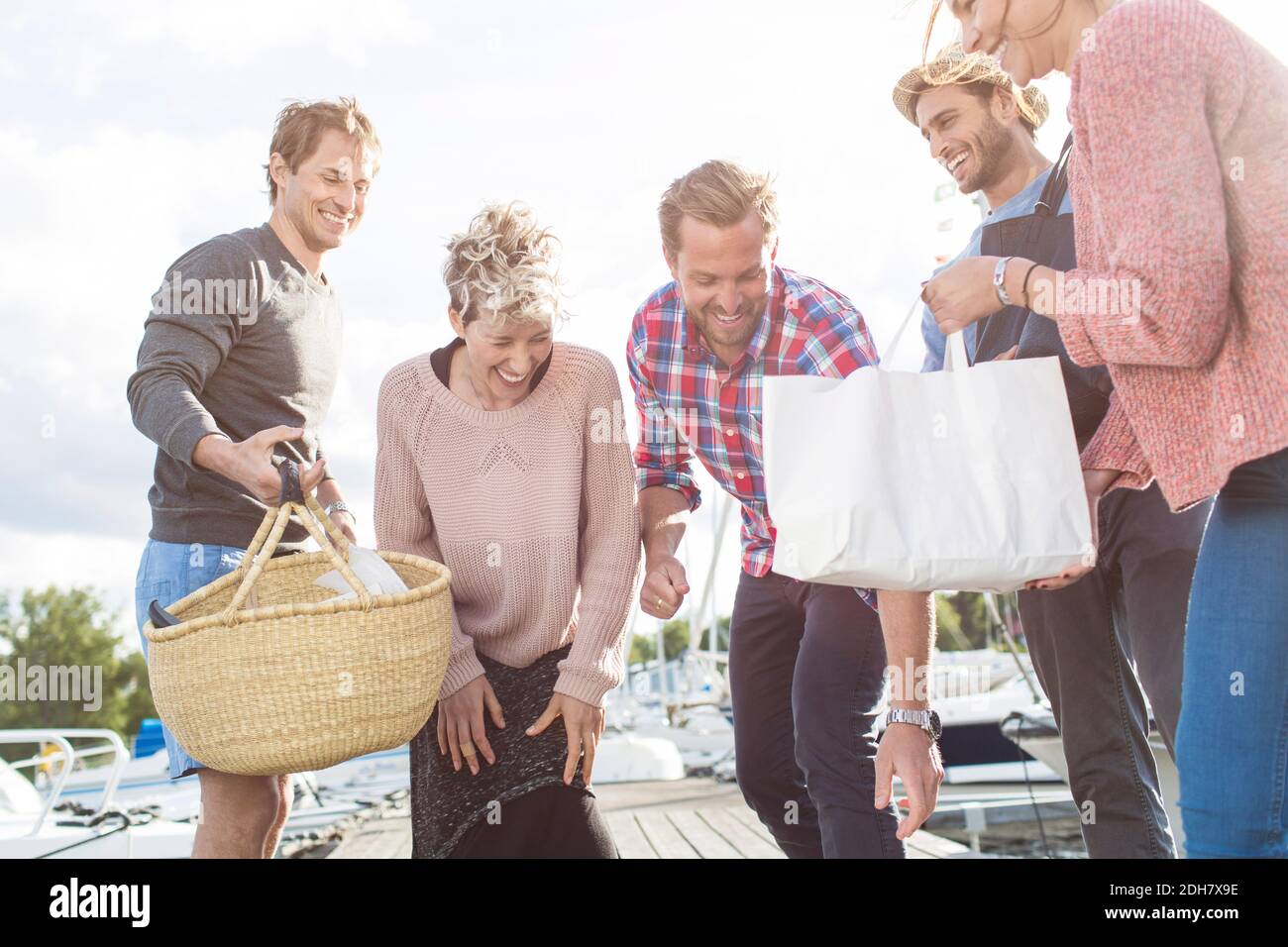 Happy friends preparing for picnic on pier at harbor Stock Photo