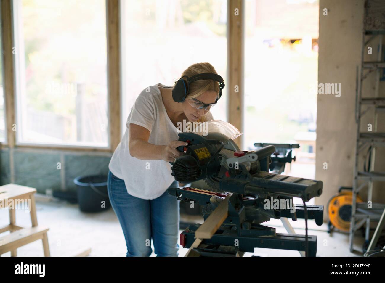 Woman cutting wood with circular saw during home improvement Stock Photo