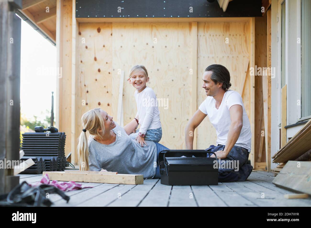 Happy family with toolbox sitting outside house Stock Photo