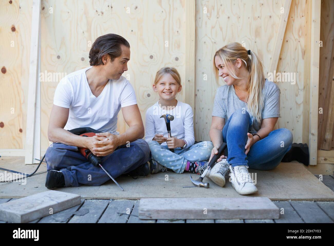Family sitting on porch of house being renovated Stock Photo
