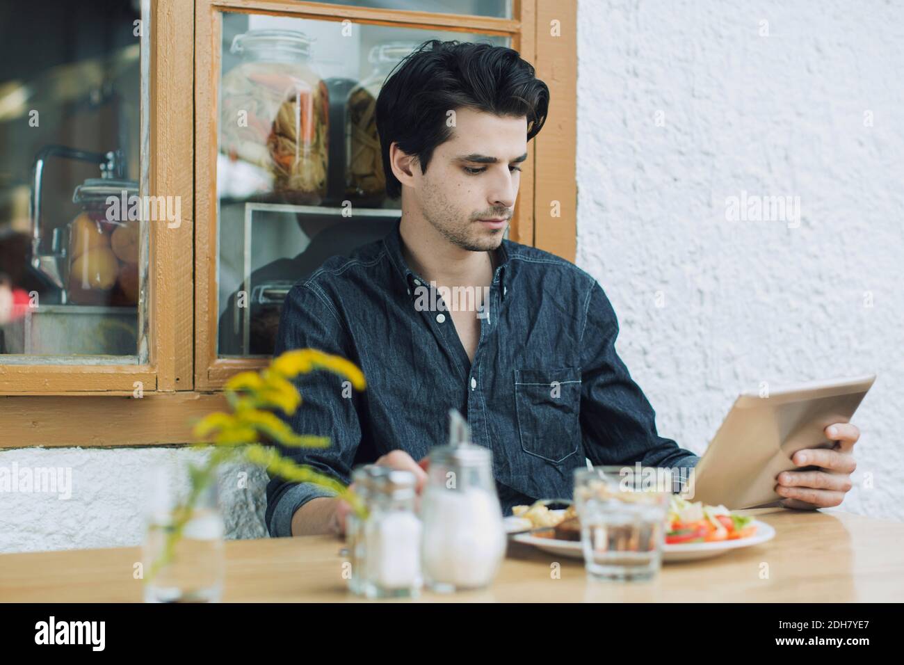 Man using digital tablet while having lunch at cafe Stock Photo