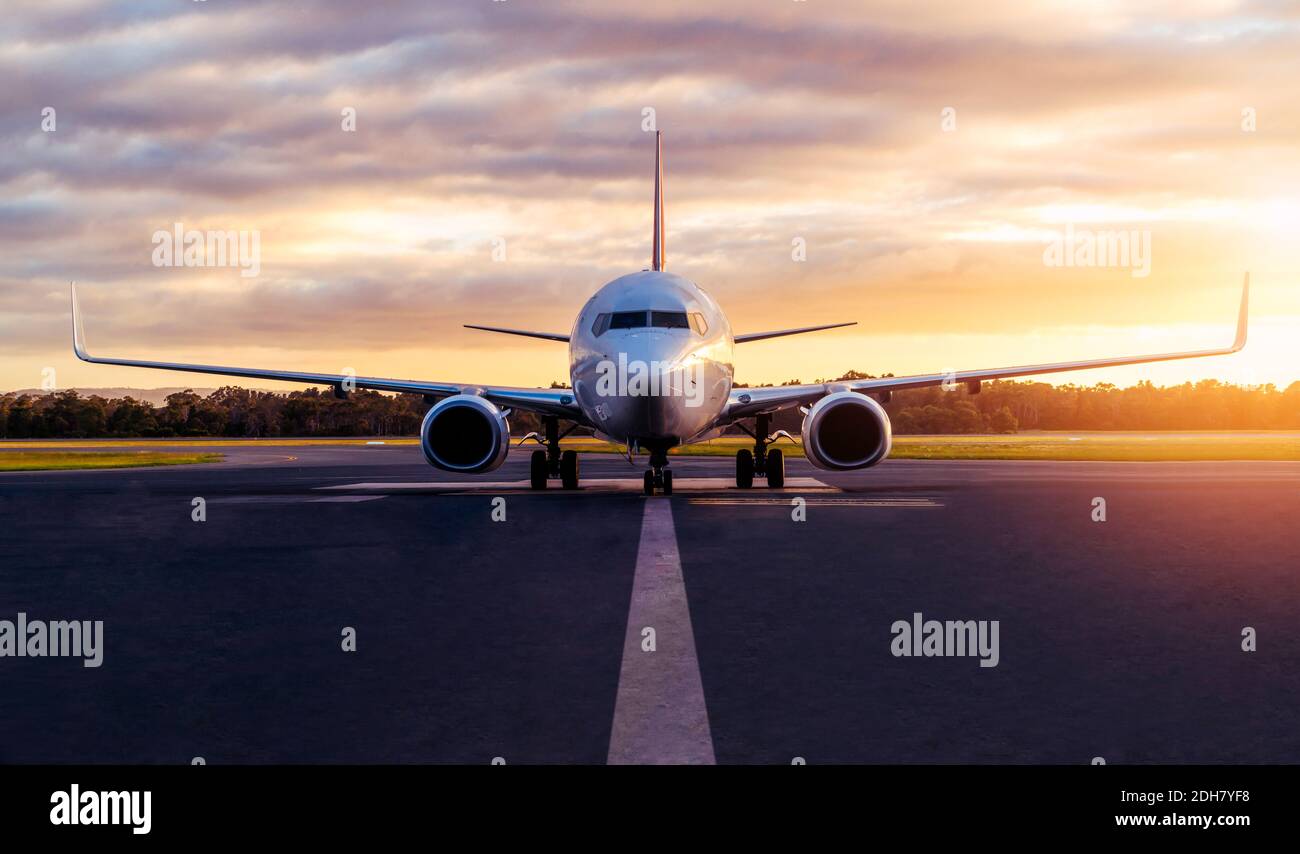 Sunset view of airplane on airport runway under dramatic sky in Hobart,Tasmania, Australia. Aviation technology and world travel concept. Stock Photo