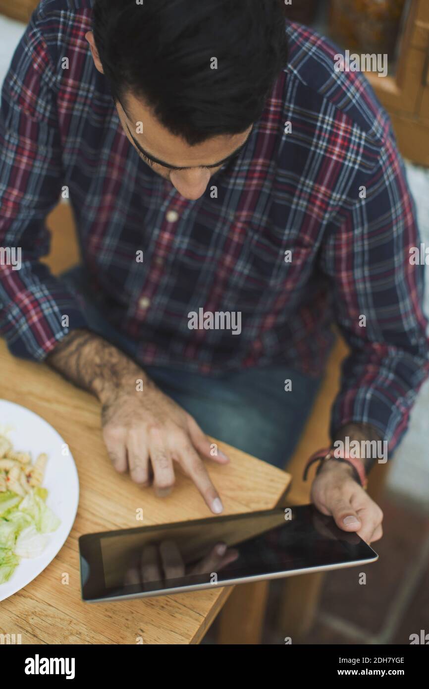 Man using digital tablet while having lunch at cafe Stock Photo