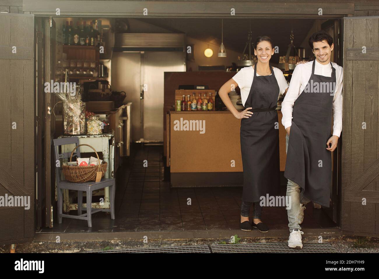 Full length portrait of smiling owners standing outside restaurant Stock Photo