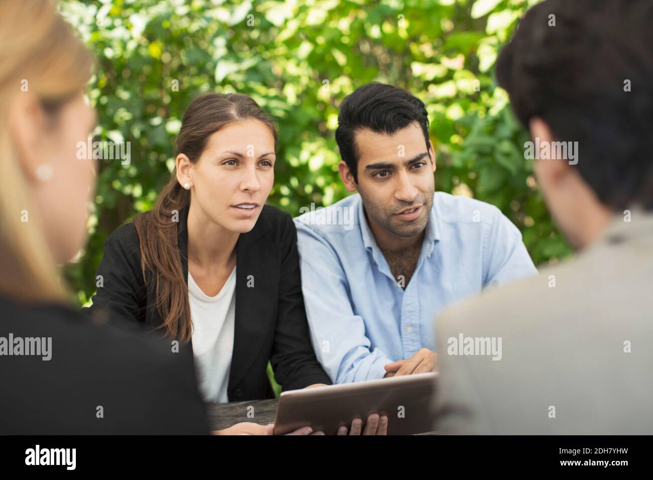 Business couples discussing using digital tablet at outdoor cafe Stock Photo