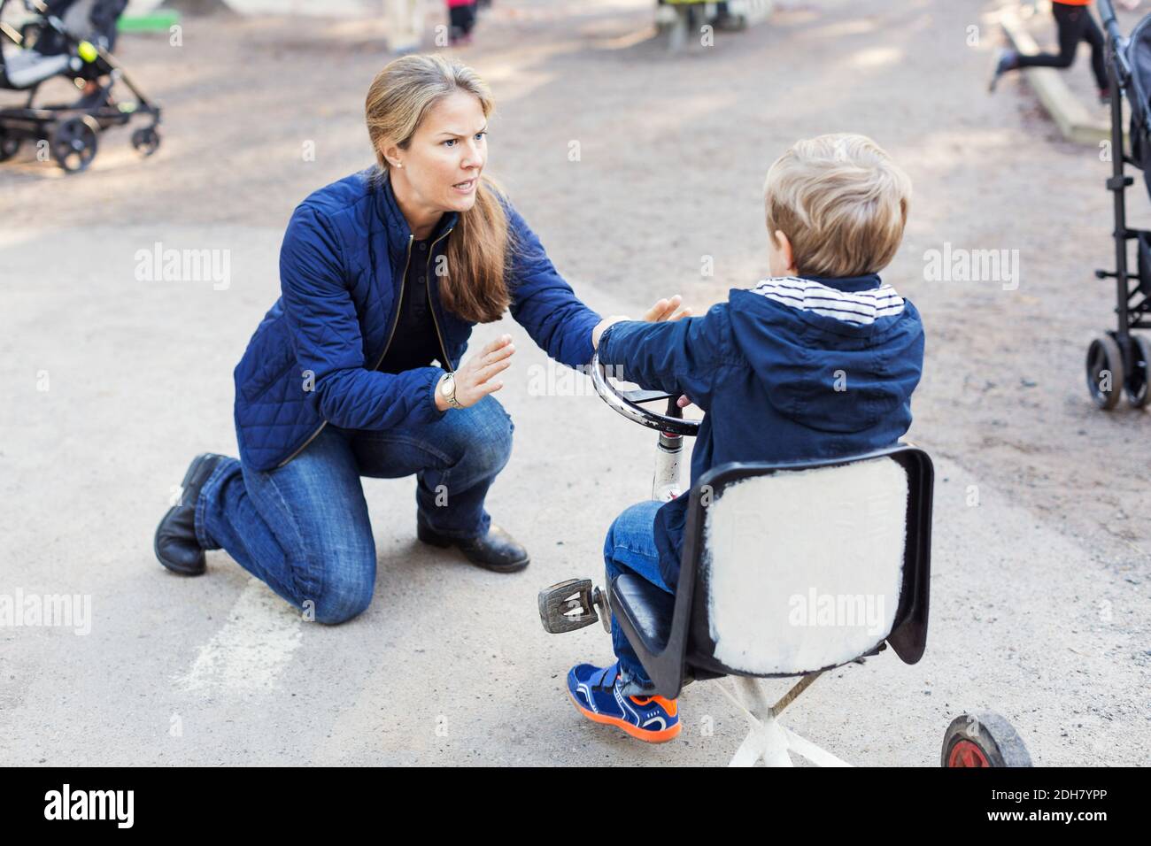Angry teacher shouting at boy on tricycle Stock Photo