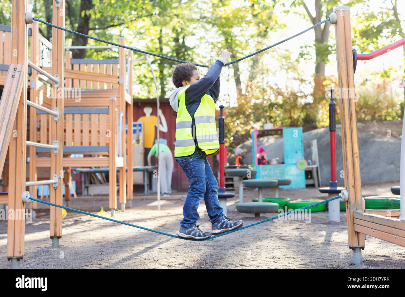 Side view of boy balancing on rope at playground Stock Photo