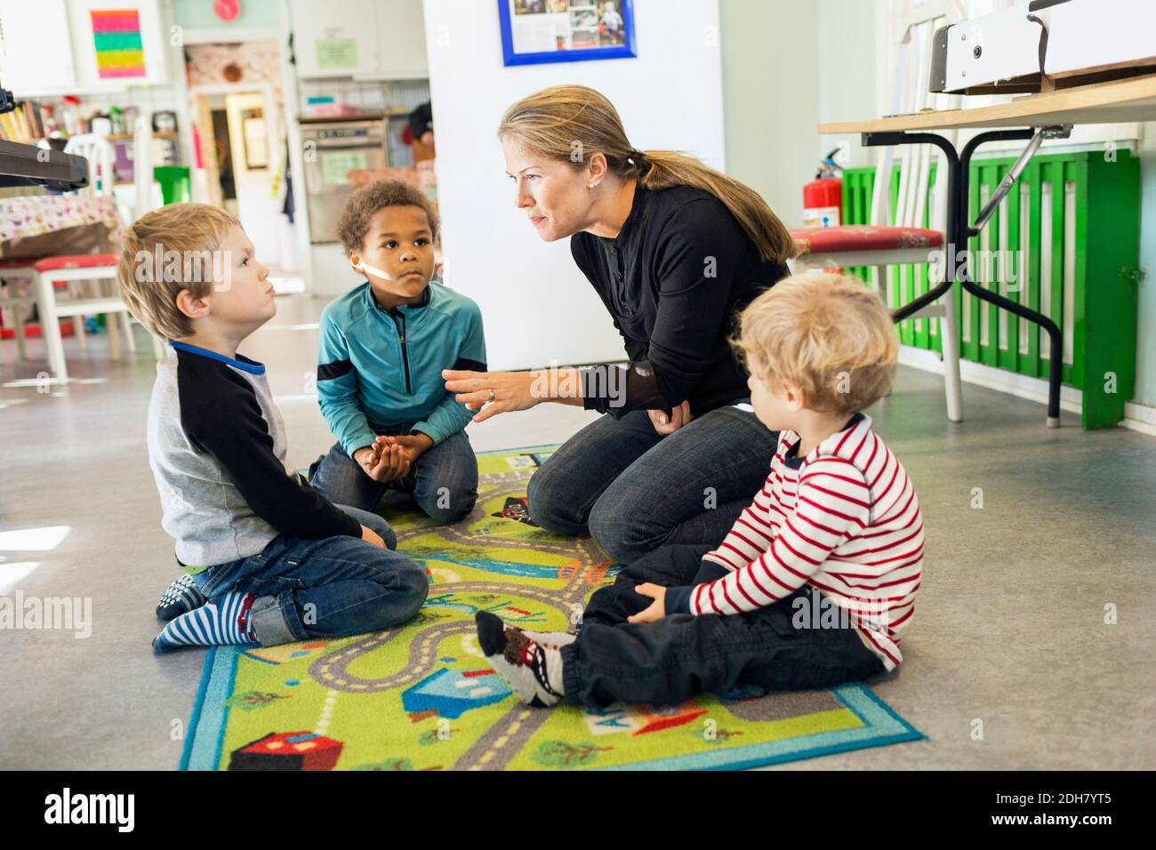 Teacher telling story to children in kindergarten Stock Photo
