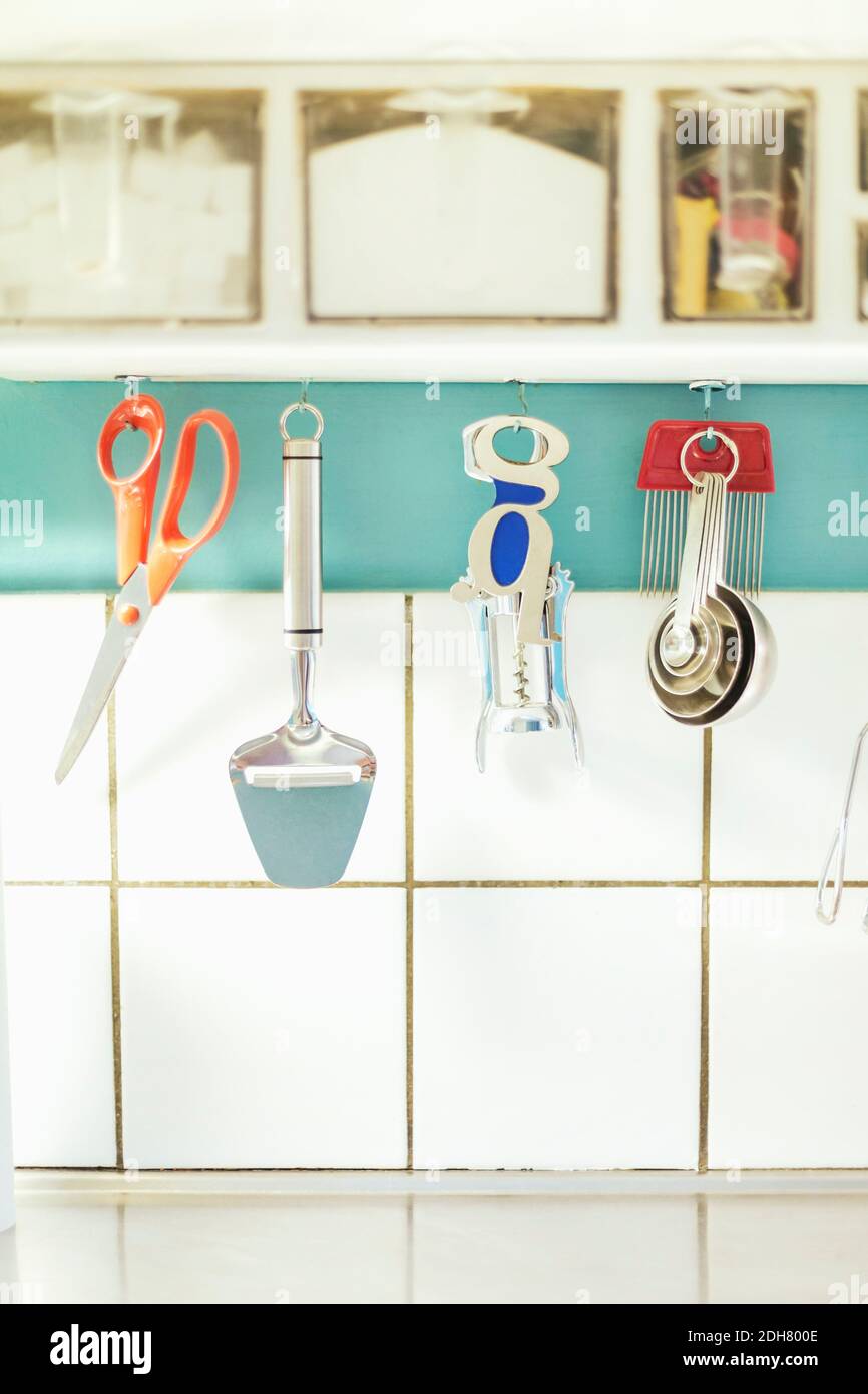 Kitchen equipment hanging on cabinet against tiled wall Stock Photo