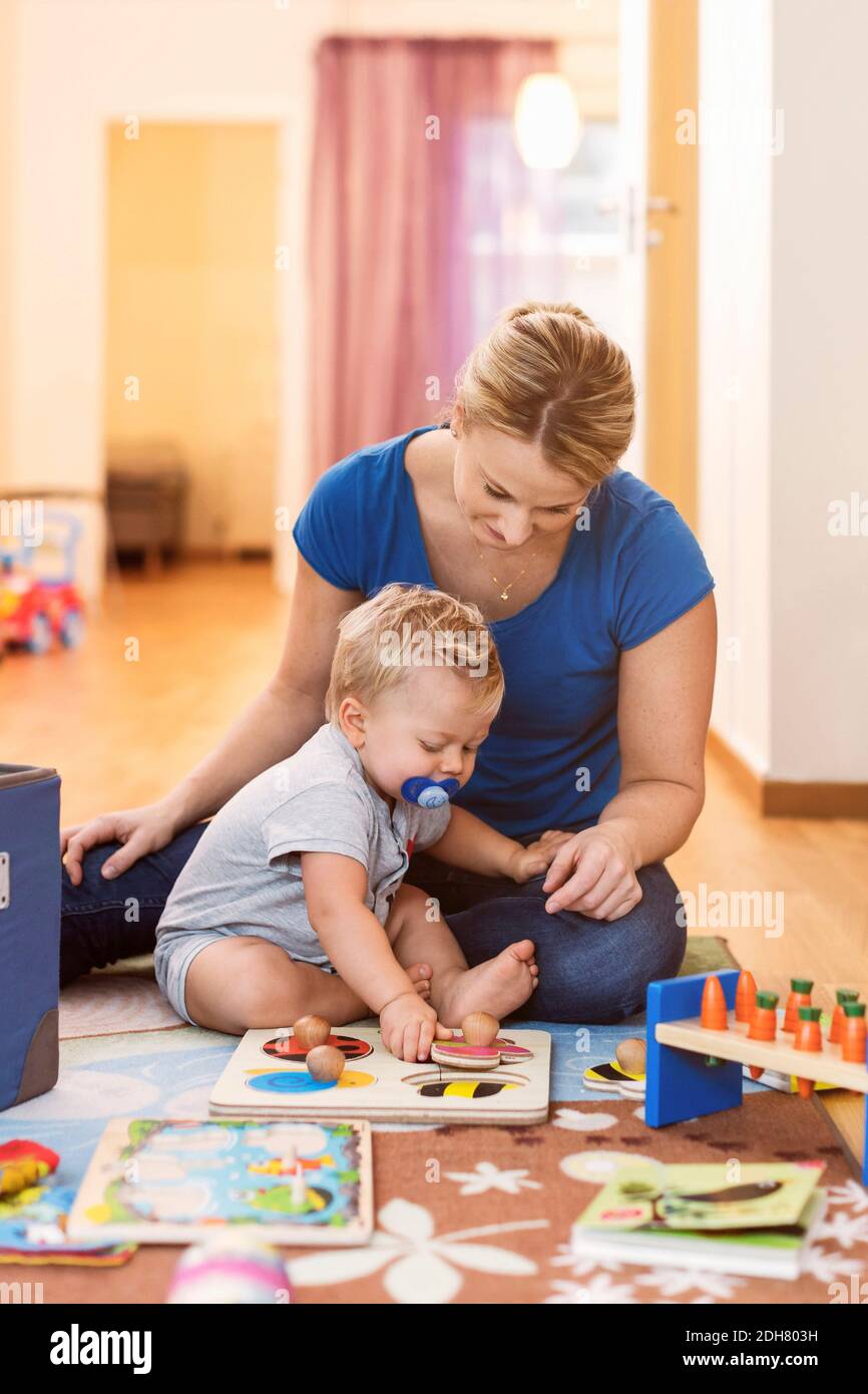Mother and baby boy playing toys on floor at home Stock Photo