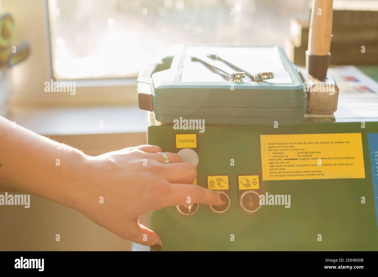 Cropped image of female mechanic's hand pressing button on machine in auto repair shop Stock Photo