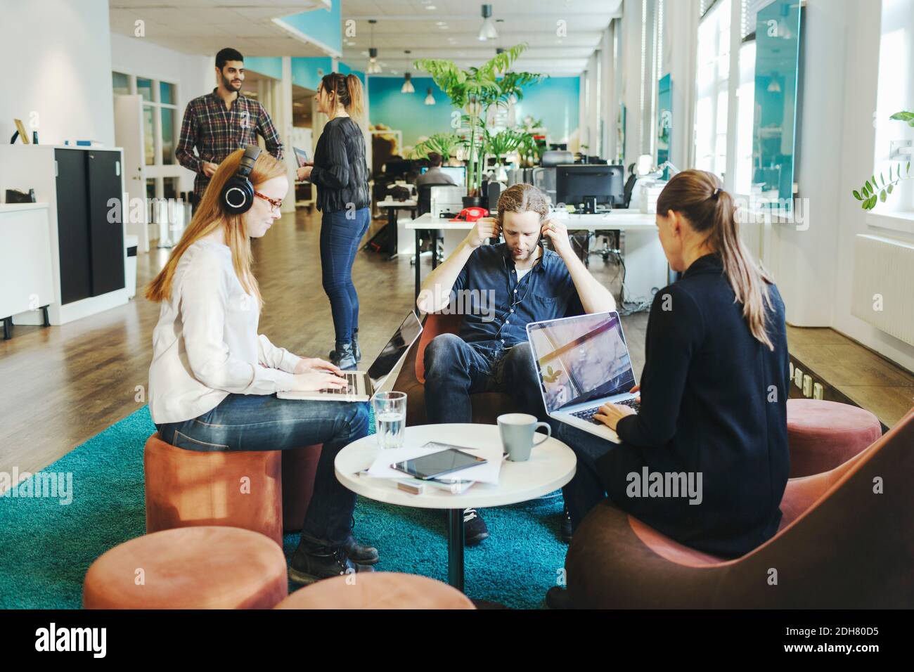 Business people using laptops in creative office Stock Photo