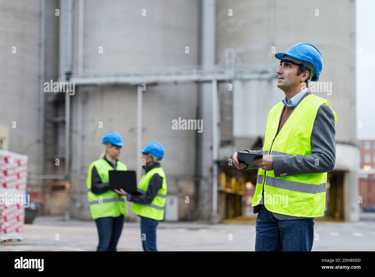 Male worker using digital tablet while looking away at factory Stock Photo