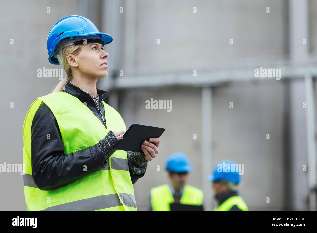 Female worker using digital tablet while looking away at factory Stock Photo