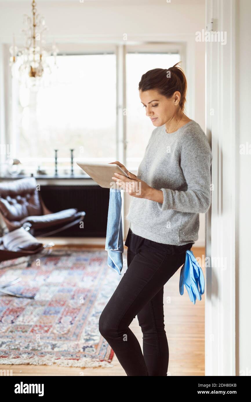 Woman using digital tablet while cleaning home Stock Photo