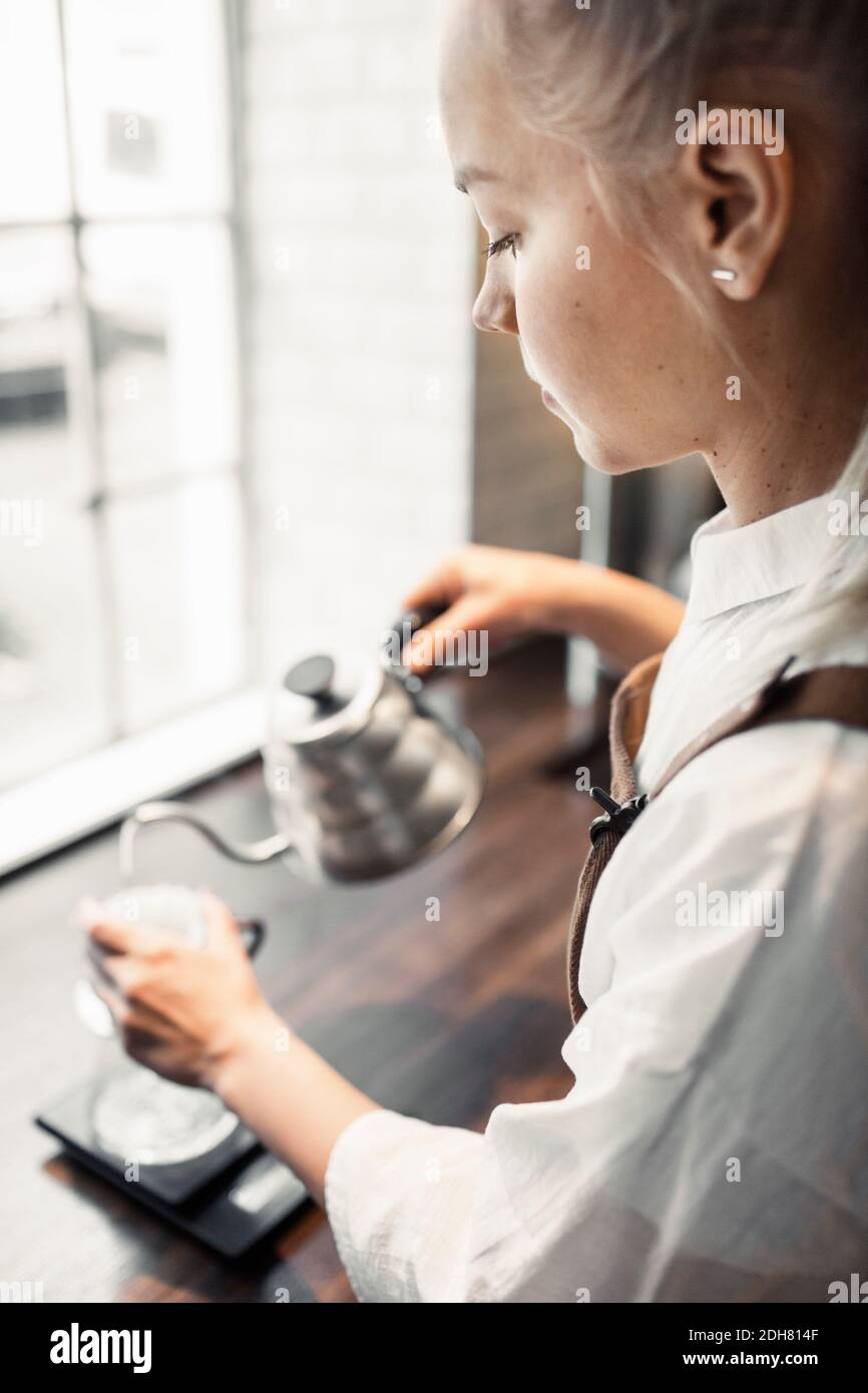 Side view of barista pouring boiling water in coffee filter Stock Photo