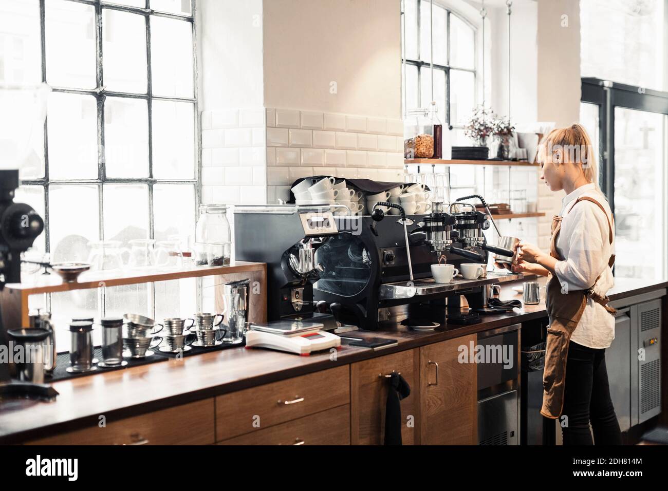 Female barista using coffee machine at cafe Stock Photo