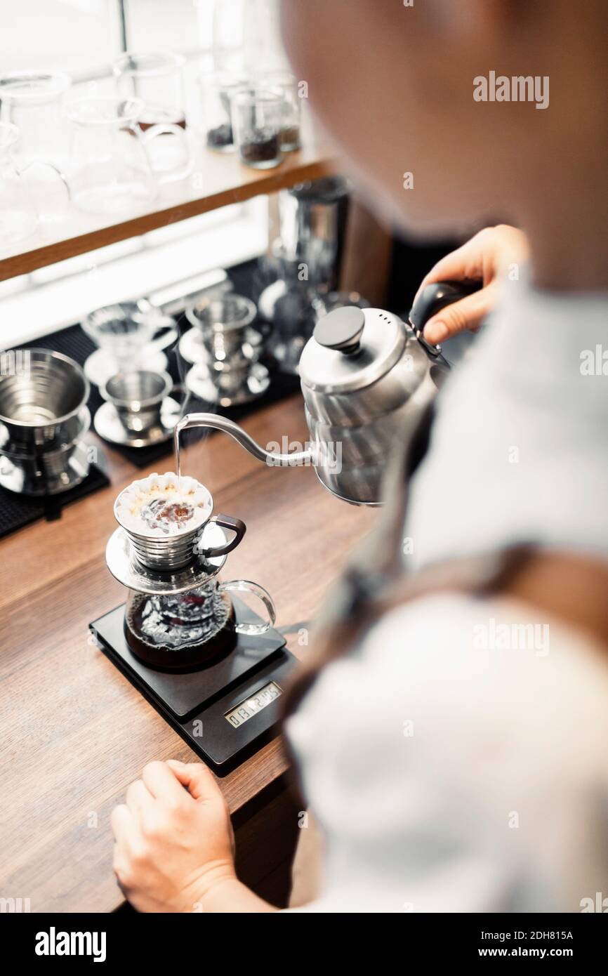 High angle cropped image of barista pouring boiling water in coffee
