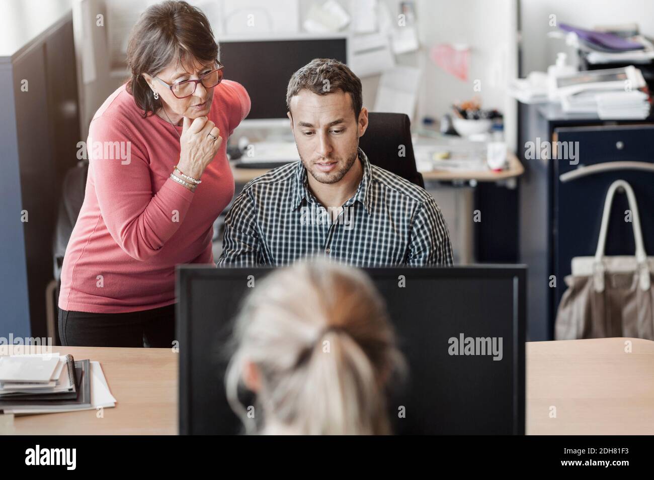 Colleagues using computer at desk in office Stock Photo