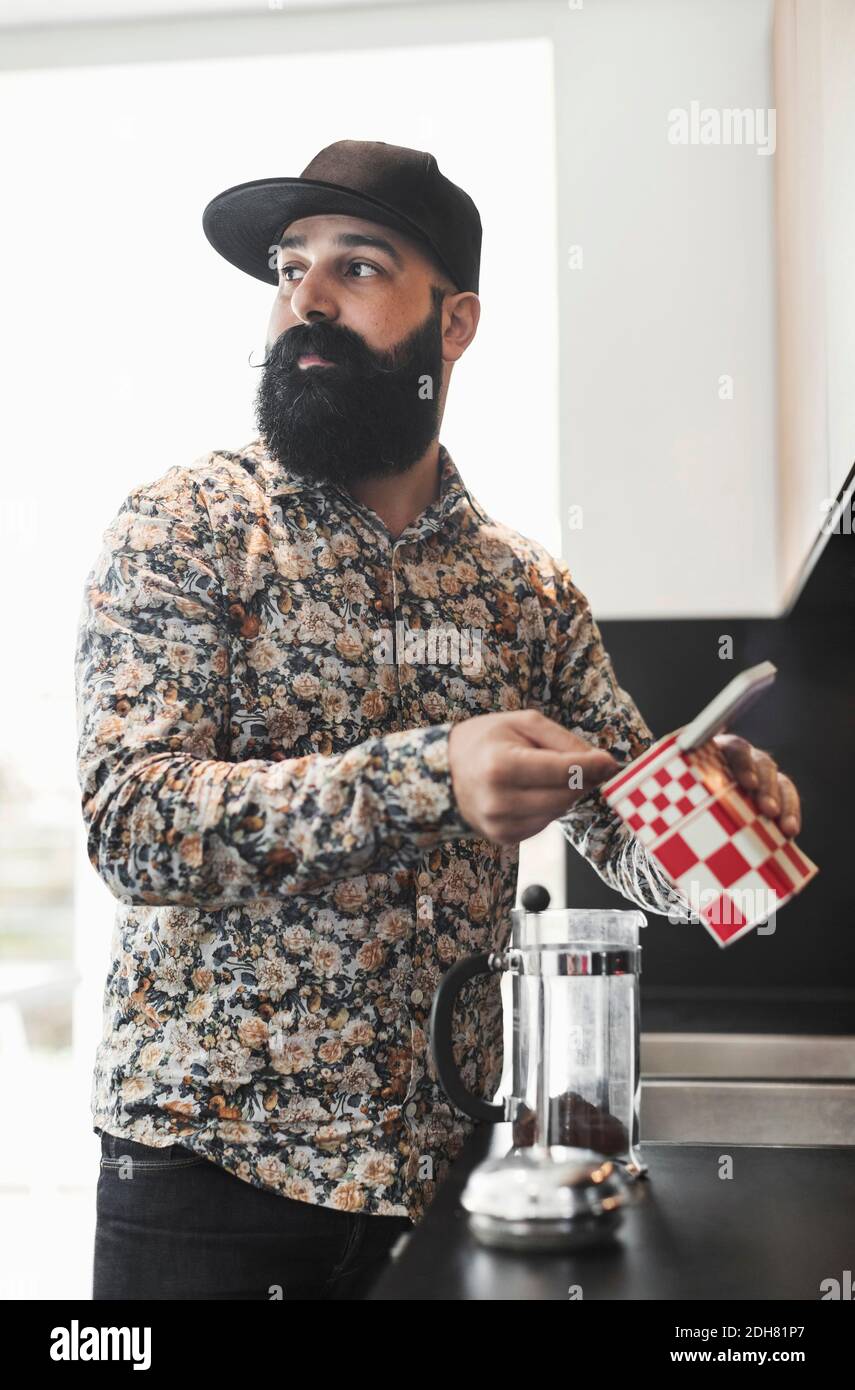 Man looking away while preparing coffee in kitchen Stock Photo