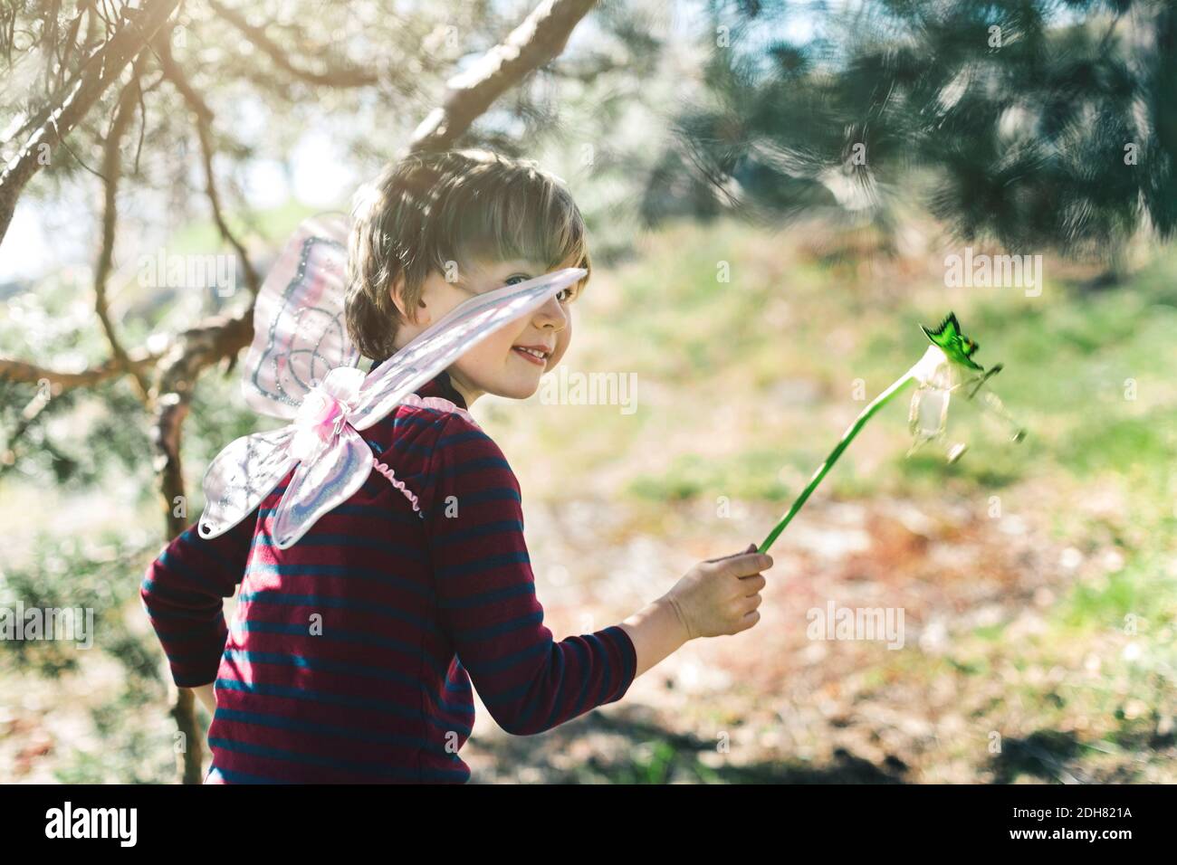 Smiling boy in fairy wings looking away at yard Stock Photo