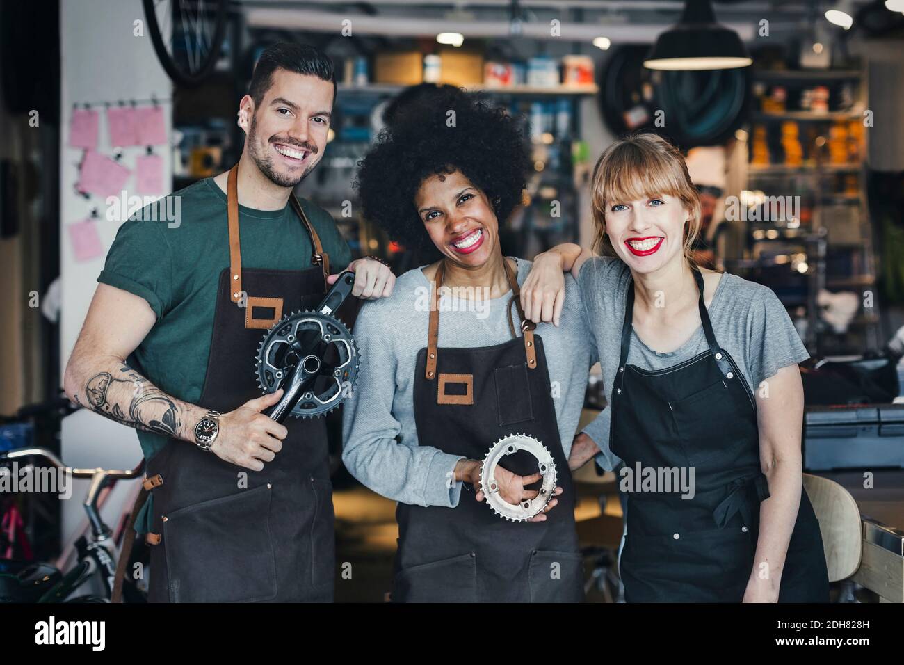 Portrait of happy multi-ethnic mechanics with gears in workshop Stock Photo