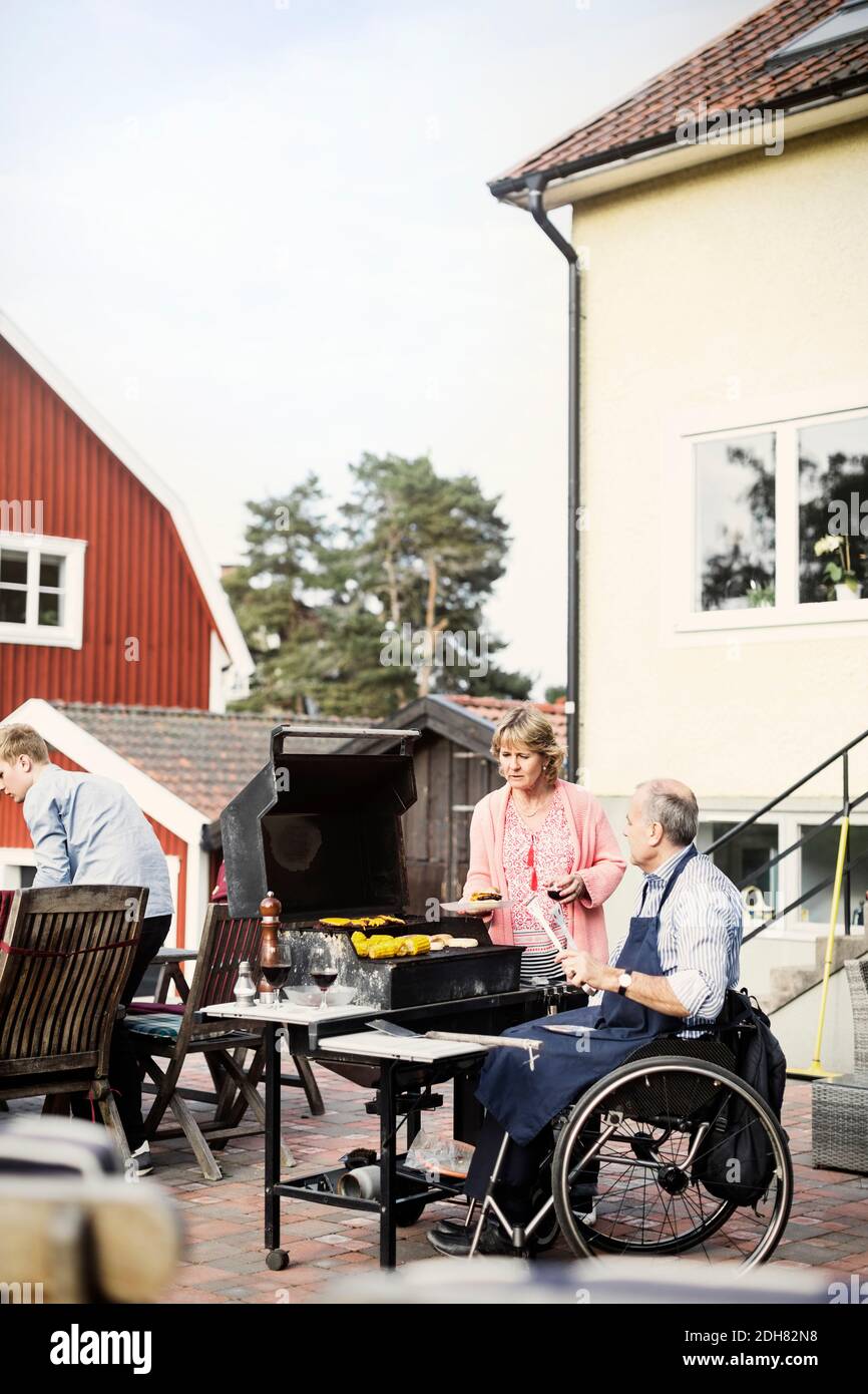 Disabled man with family barbecuing at yard Stock Photo