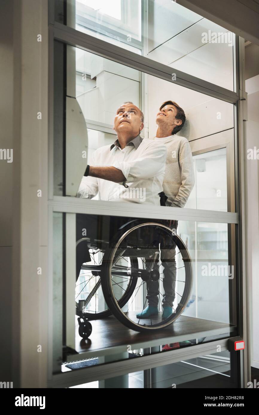 son and father in wheelchair lift at home Stock Photo