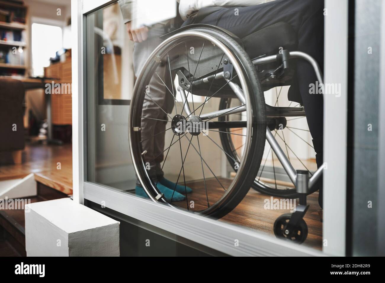 Low section of son and father in wheelchair lift at home Stock Photo
