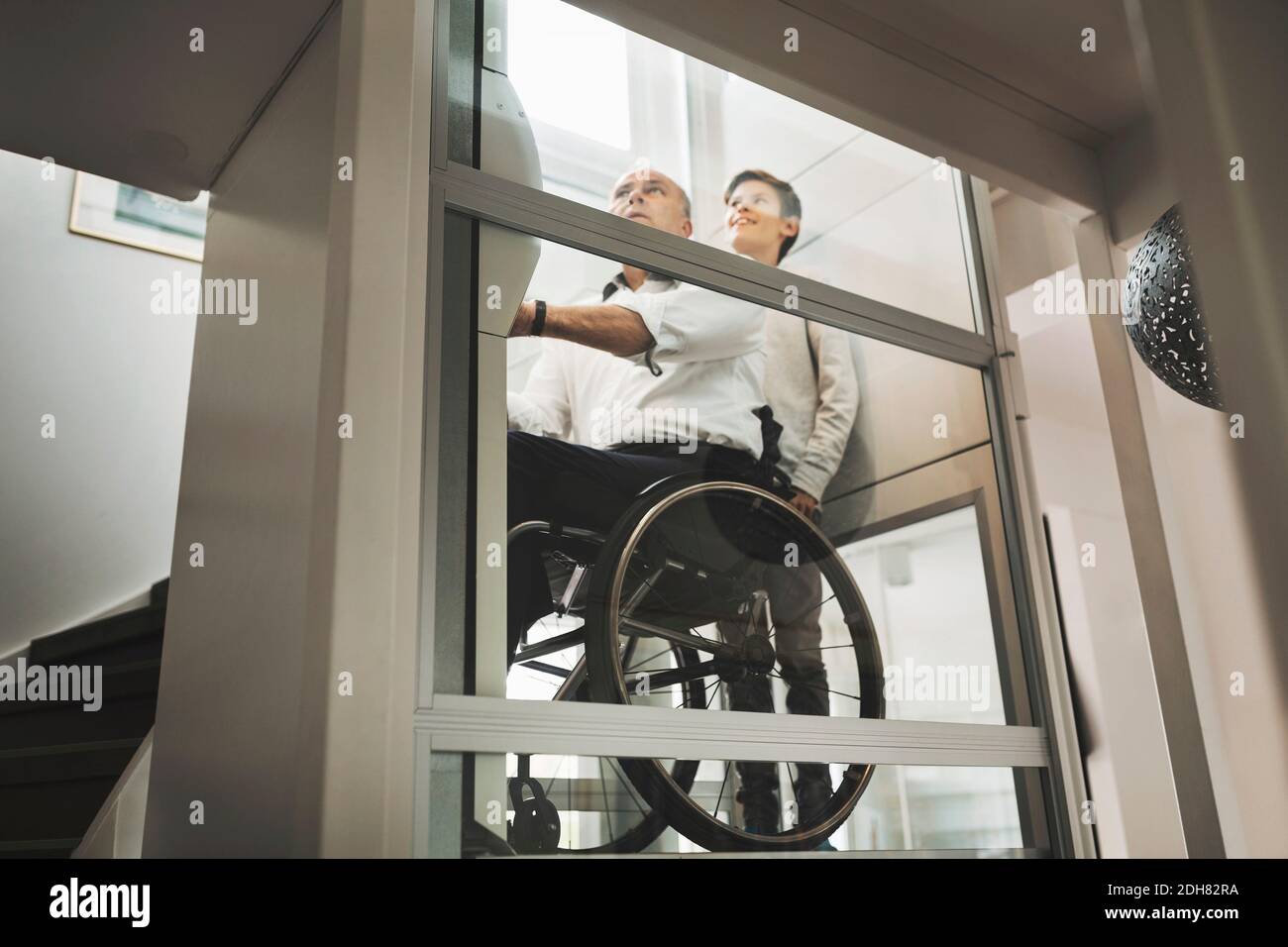 Low angle view of son and father in wheelchair lift at home Stock Photo