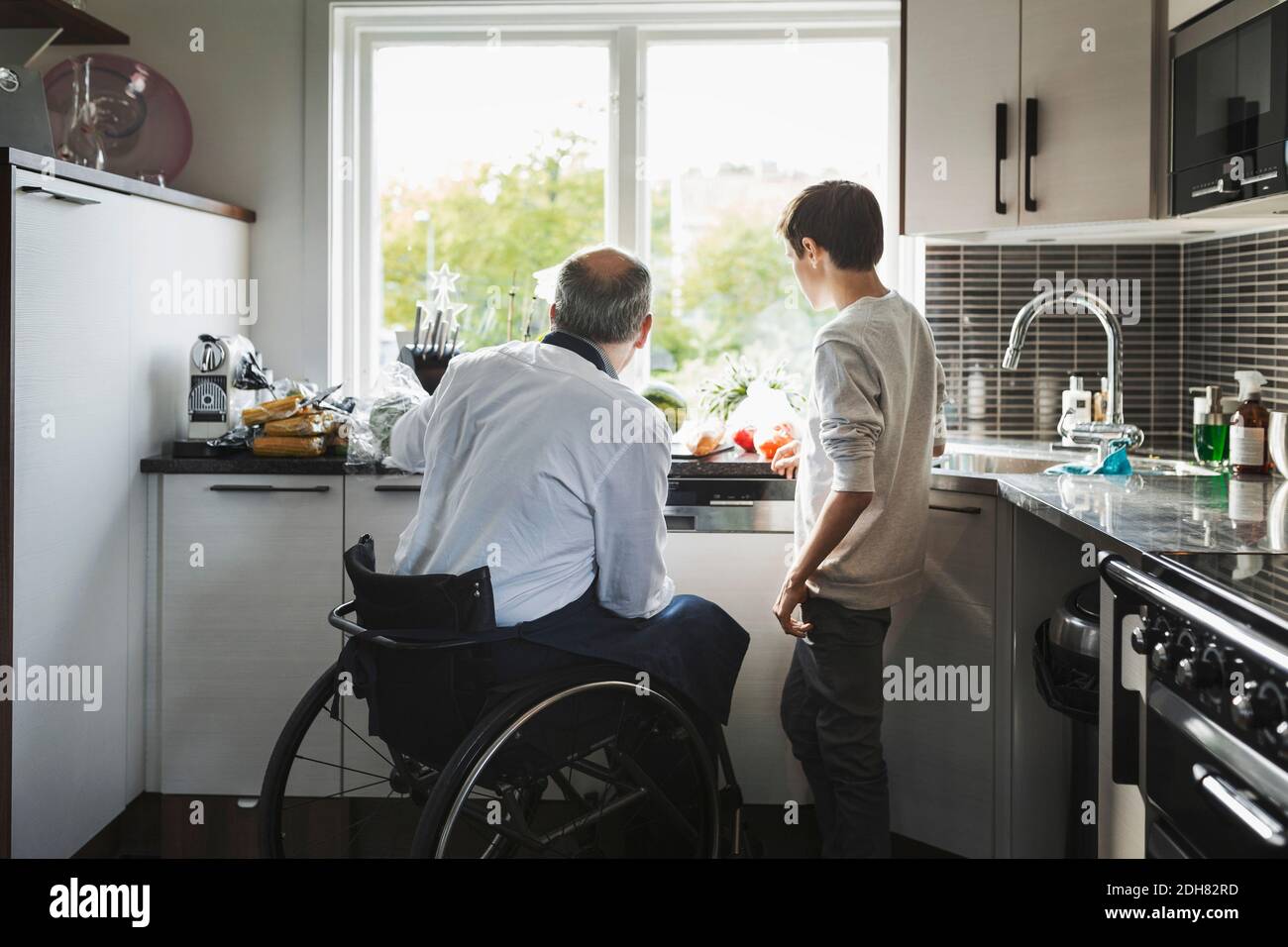 Disabled father preparing food son in kitchen Stock Photo