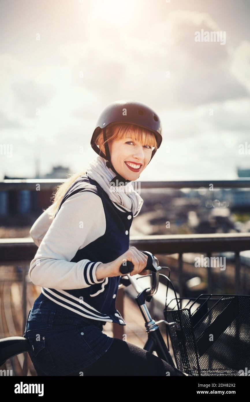 Side view portrait of happy businesswoman standing with bicycle on bridge Stock Photo