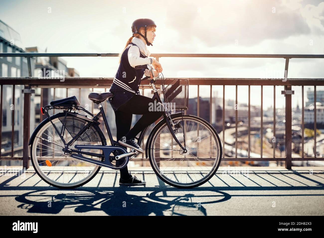 Side view of businesswoman with bicycle standing on bridge Stock Photo