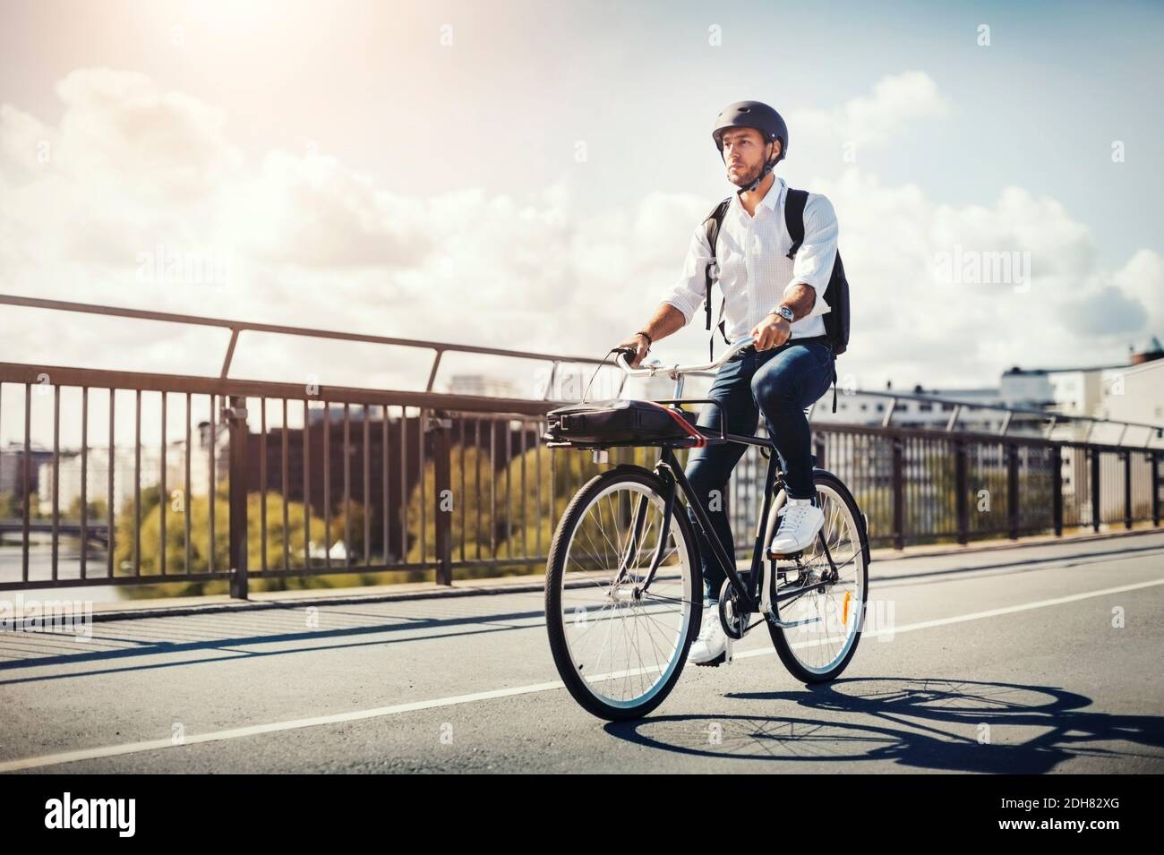 Businessman riding bicycle on bridge against sky Stock Photo