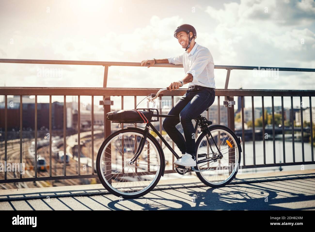 Happy businessman with bicycle on bridge in city Stock Photo