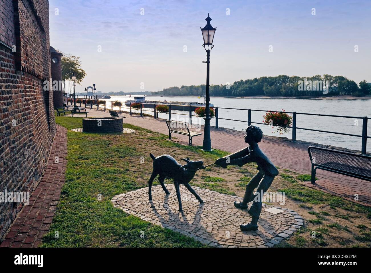 bronze sculpture 'goat' at the Rhine promenade in Rees, inland vessel in the background, Germany, North Rhine-Westphalia, Lower Rhine, Rees Stock Photo