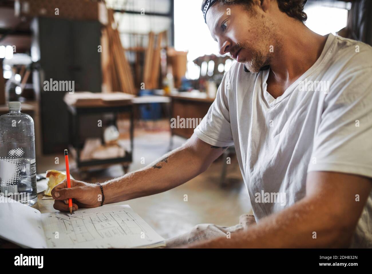 Carpenter using mobile phone while reading document in workshop Stock Photo
