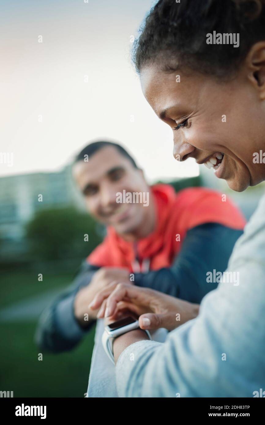 Smiling woman using smart watch while standing by friend Stock Photo