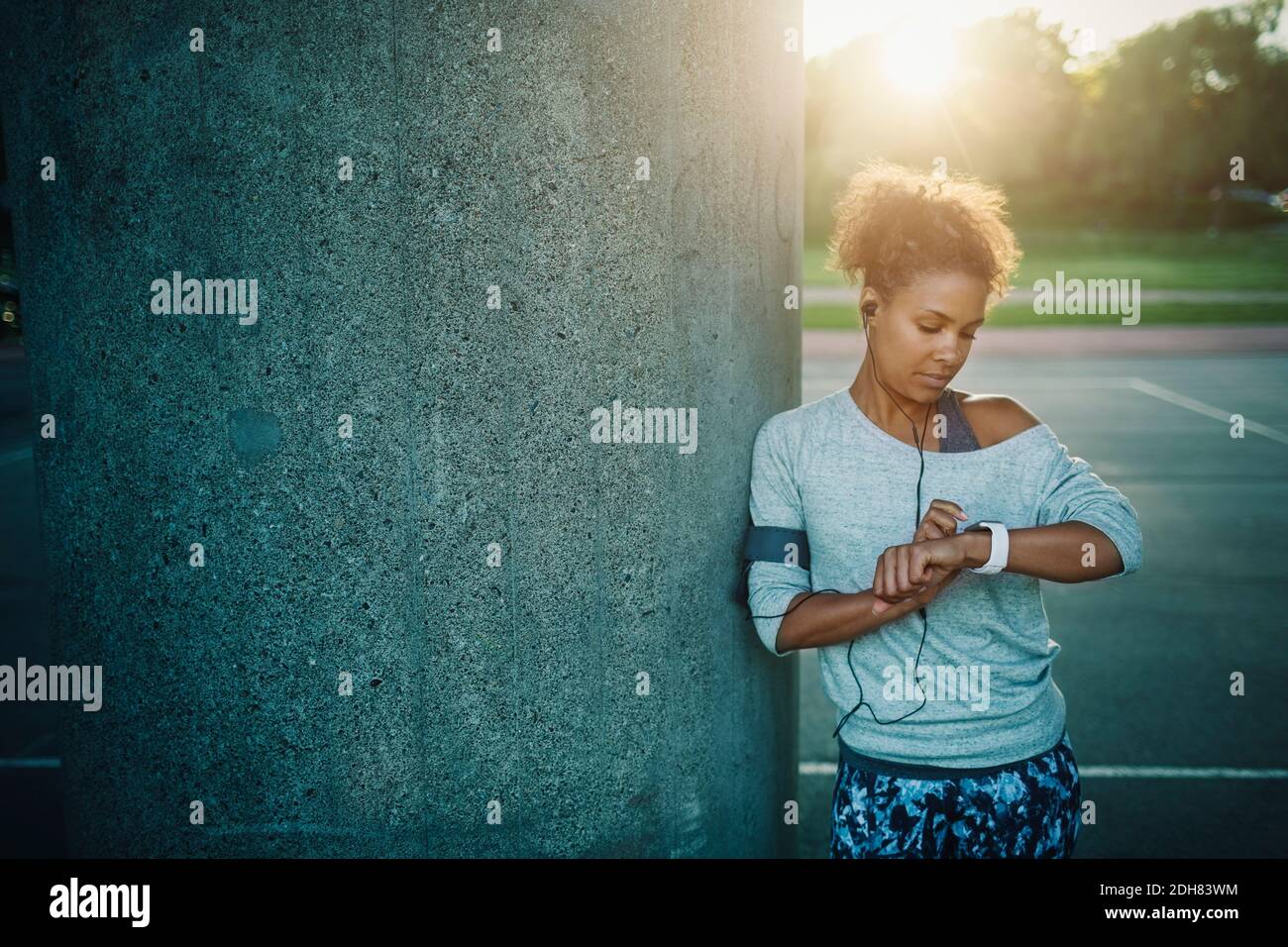 Woman using smart watch while standing by column Stock Photo