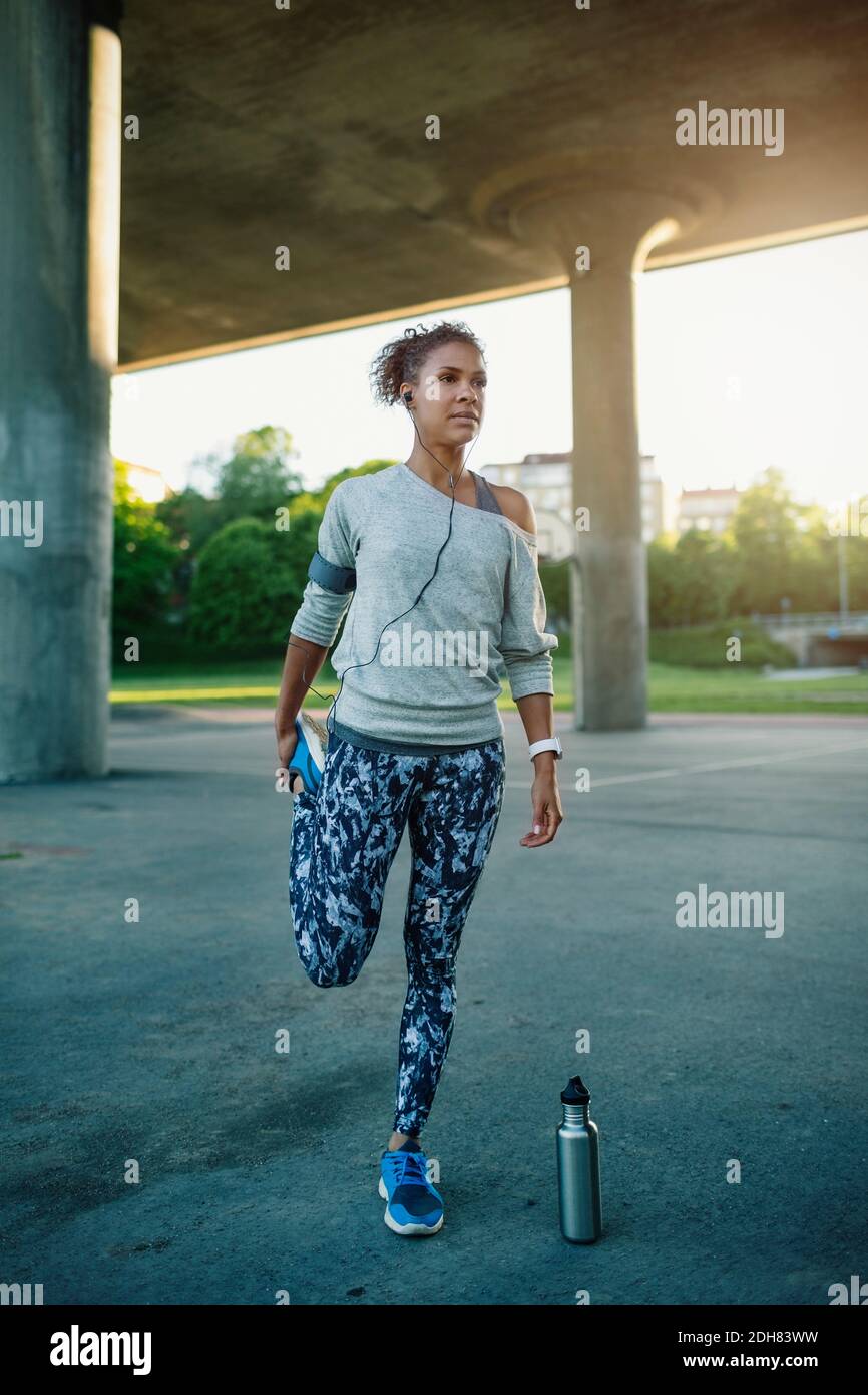 Woman listening music while stretching and standing on one leg Stock Photo