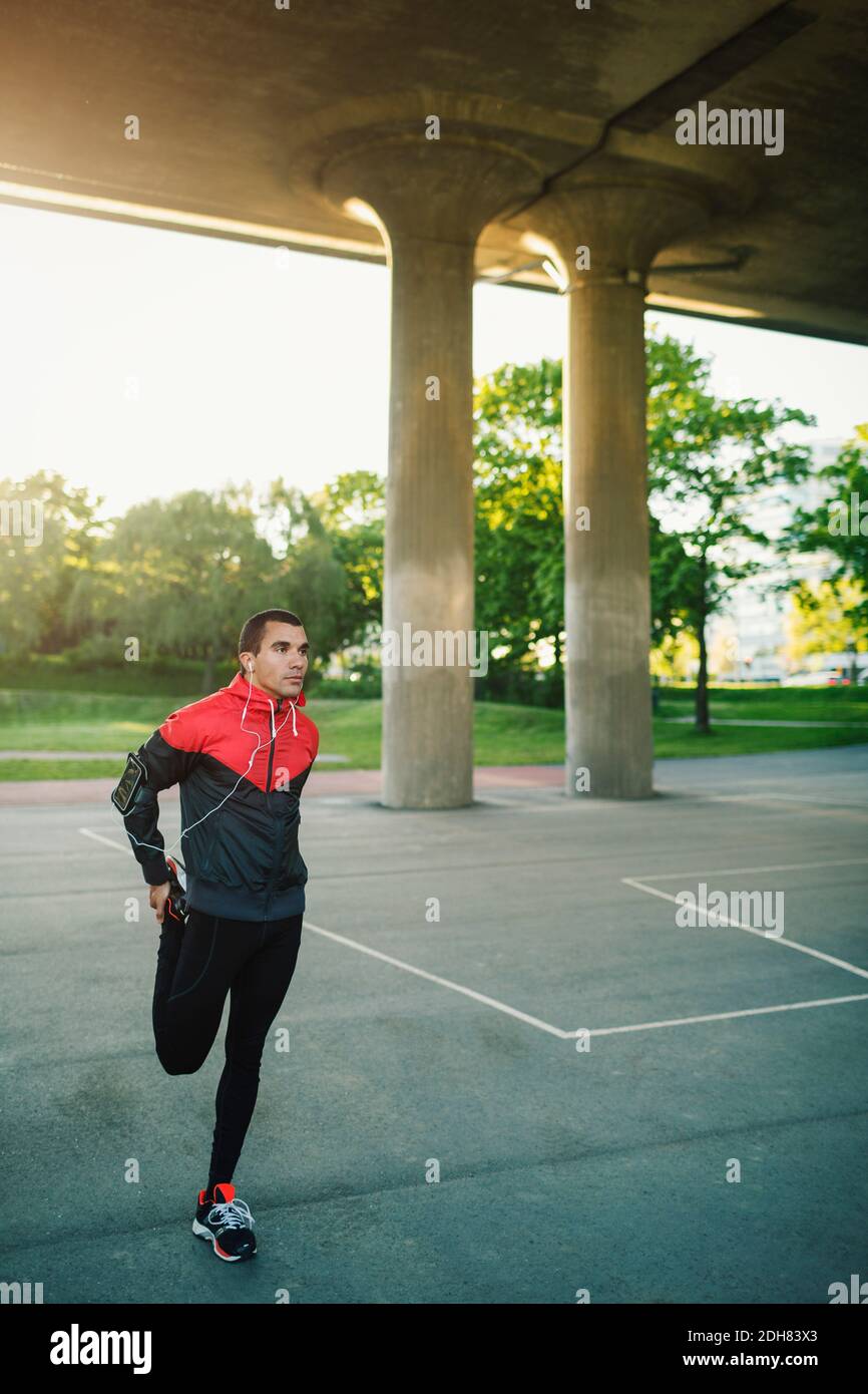 Man wearing hooded shirt stretching and standing on one leg Stock Photo