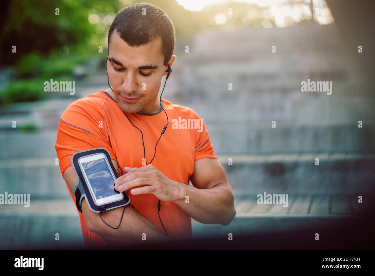 Man using smart phone armband while standing at steps Stock Photo