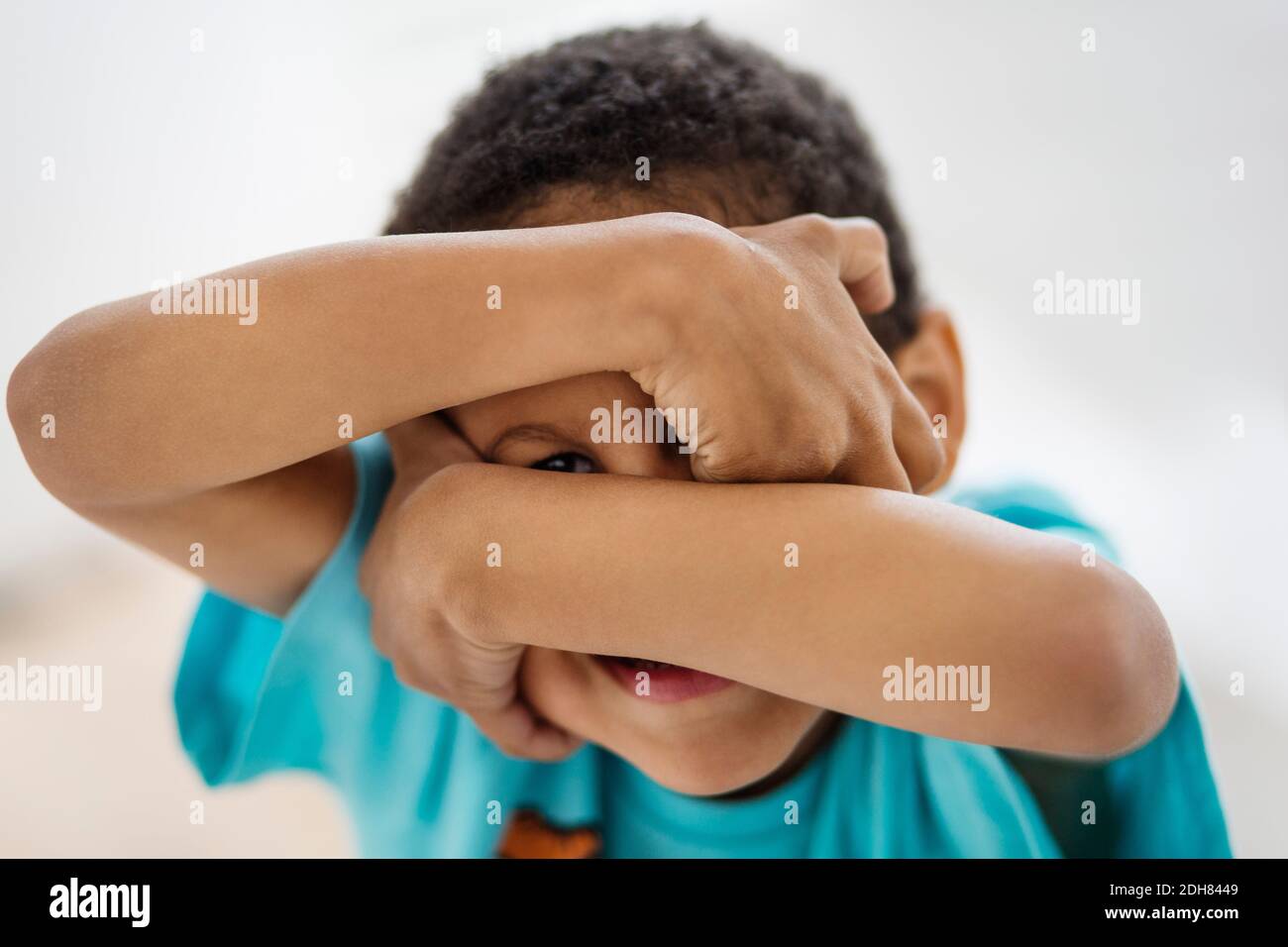 Portrait of playful boy covering face at home Stock Photo