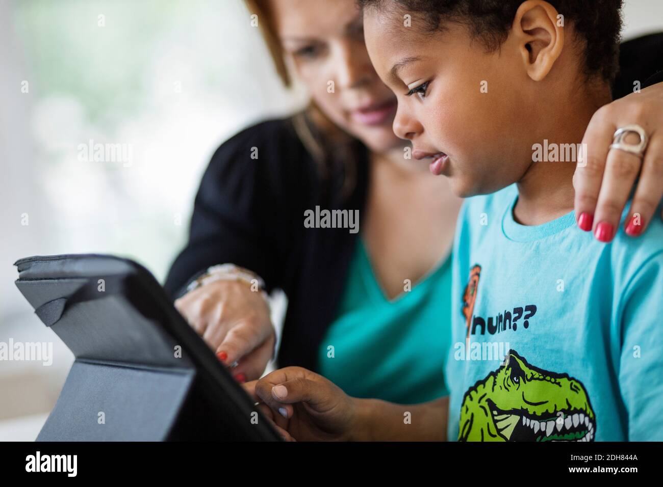 Mother assisting son in using digital tablet at home Stock Photo
