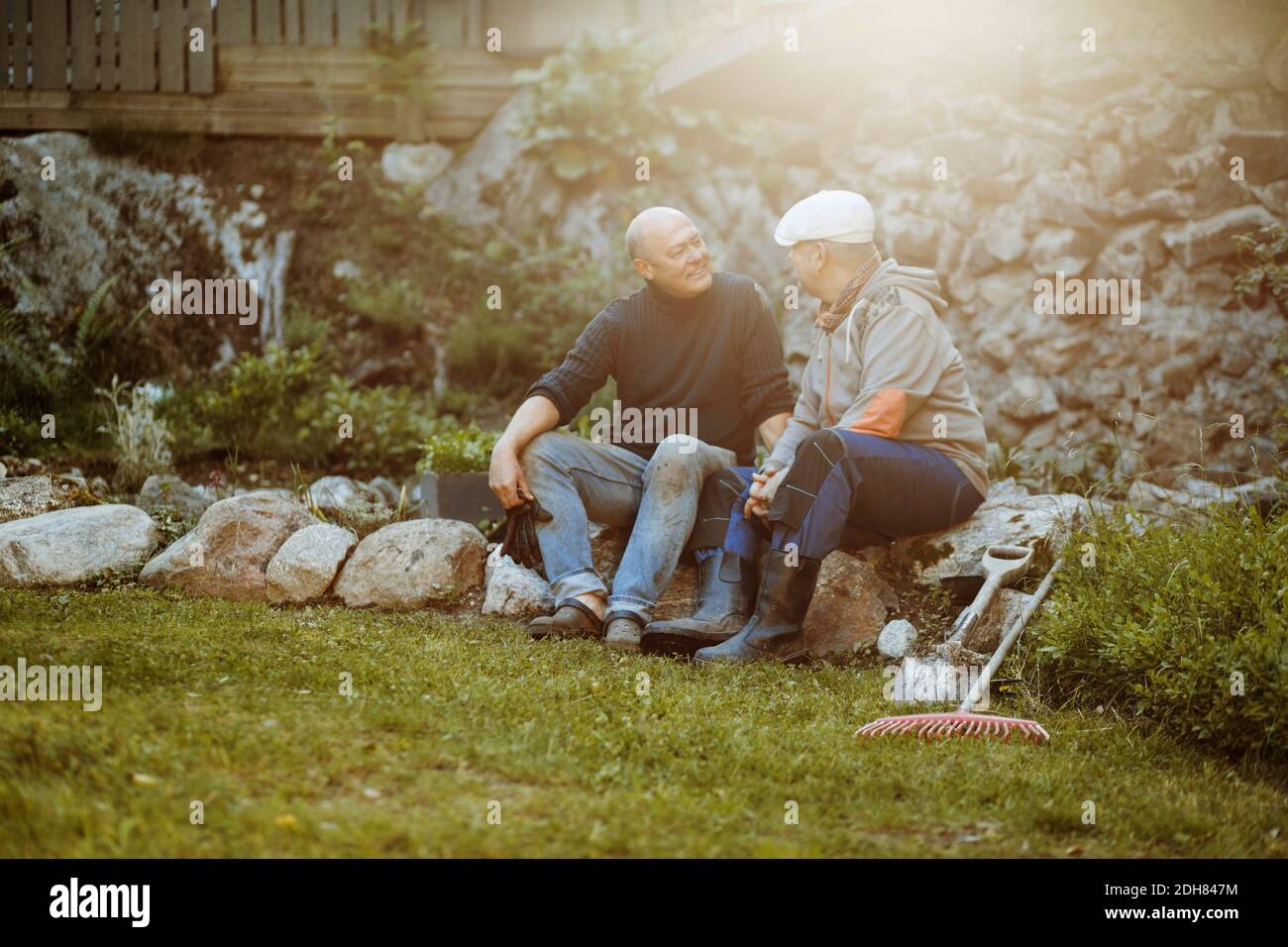 Gay men conversing while sitting on rocks at field Stock Photo