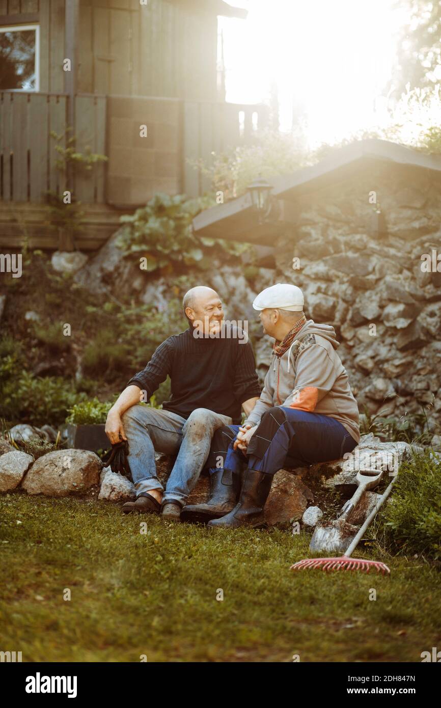 Gay couple talking while sitting on rocks at field Stock Photo