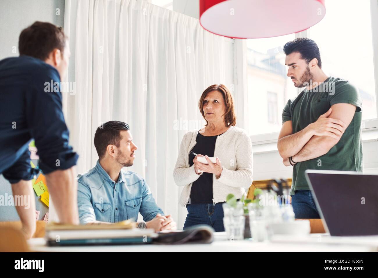 Mature businesswoman with male colleagues discussing project in office Stock Photo