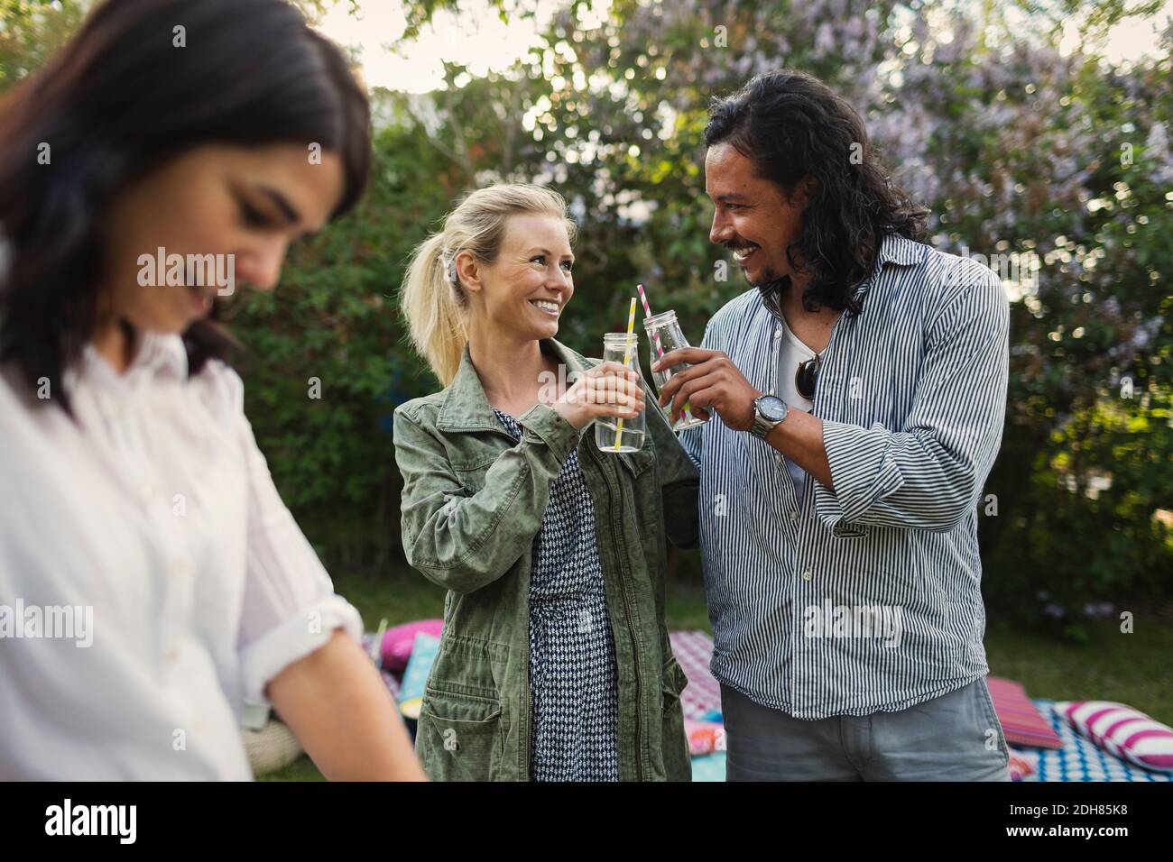 Happy Couple Toasting Drink Bottles During Summer Party In Yard Stock 