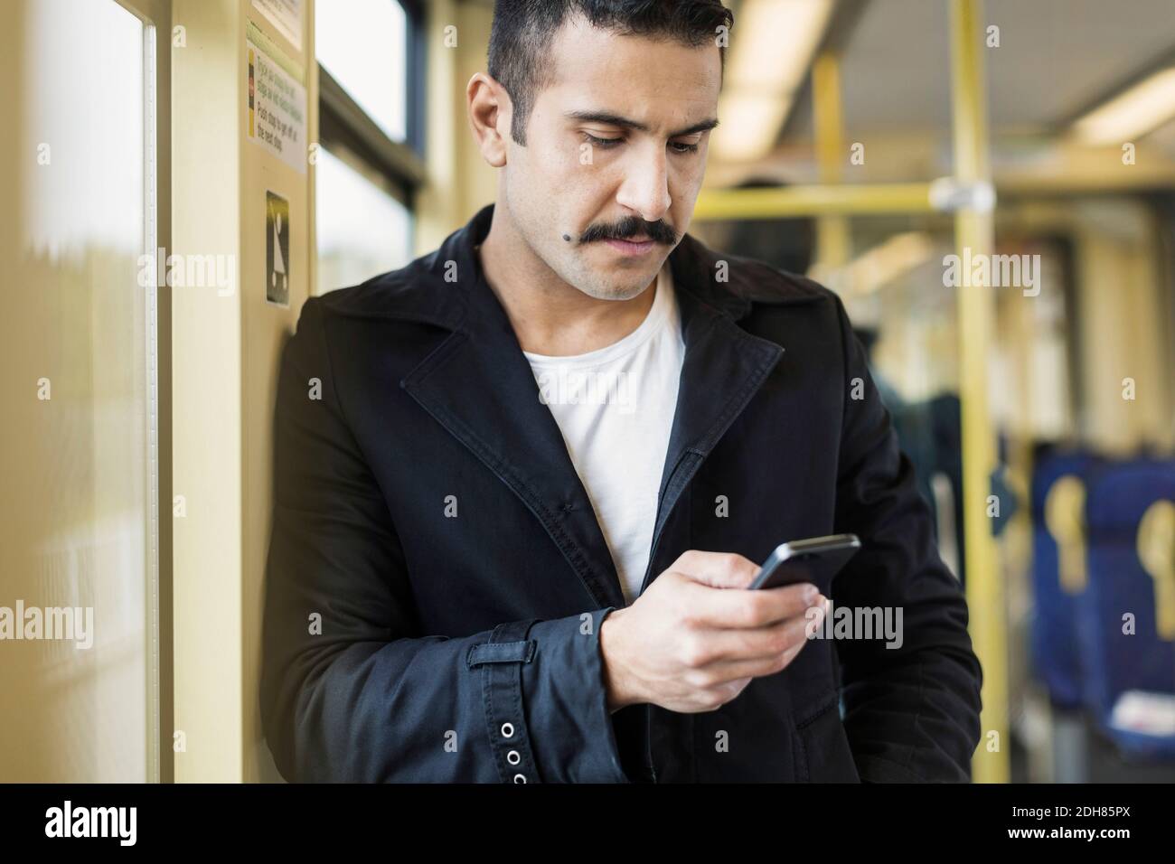 Young man using mobile phone in tram Stock Photo